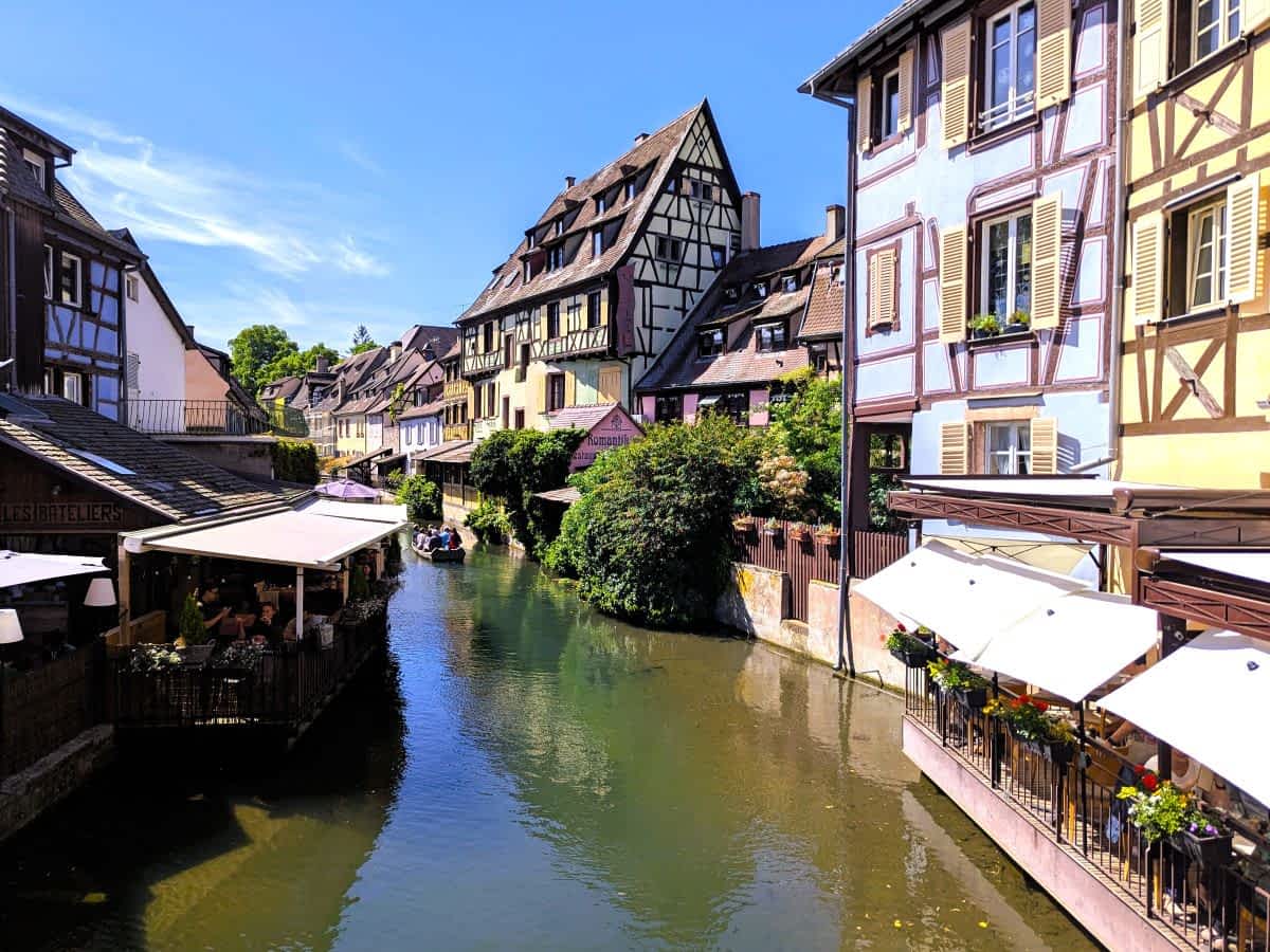 Malerischer Blick auf den Kanal in "Petite Venise" (Klein-Venedig) in Colmar, gesäumt von bunten Fachwerkhäusern und Restaurants mit Sonnenschirmen. Malerischer Blick auf den Kanal in "Petite Venise" (Klein-Venedig) in Colmar, gesäumt von bunten Fachwerkhäusern und Restaurants mit Sonnenschirmen.