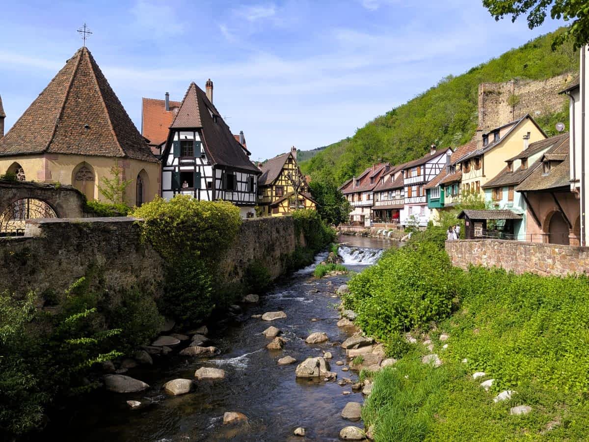 Blick flussabwärts auf den Fluss Weiss in Kaysersberg, gesäumt von historischen Fachwerkhäusern mit Blumenbalkonen. Blick flussabwärts auf den Fluss Weiss in Kaysersberg, gesäumt von historischen Fachwerkhäusern mit Blumenbalkonen.