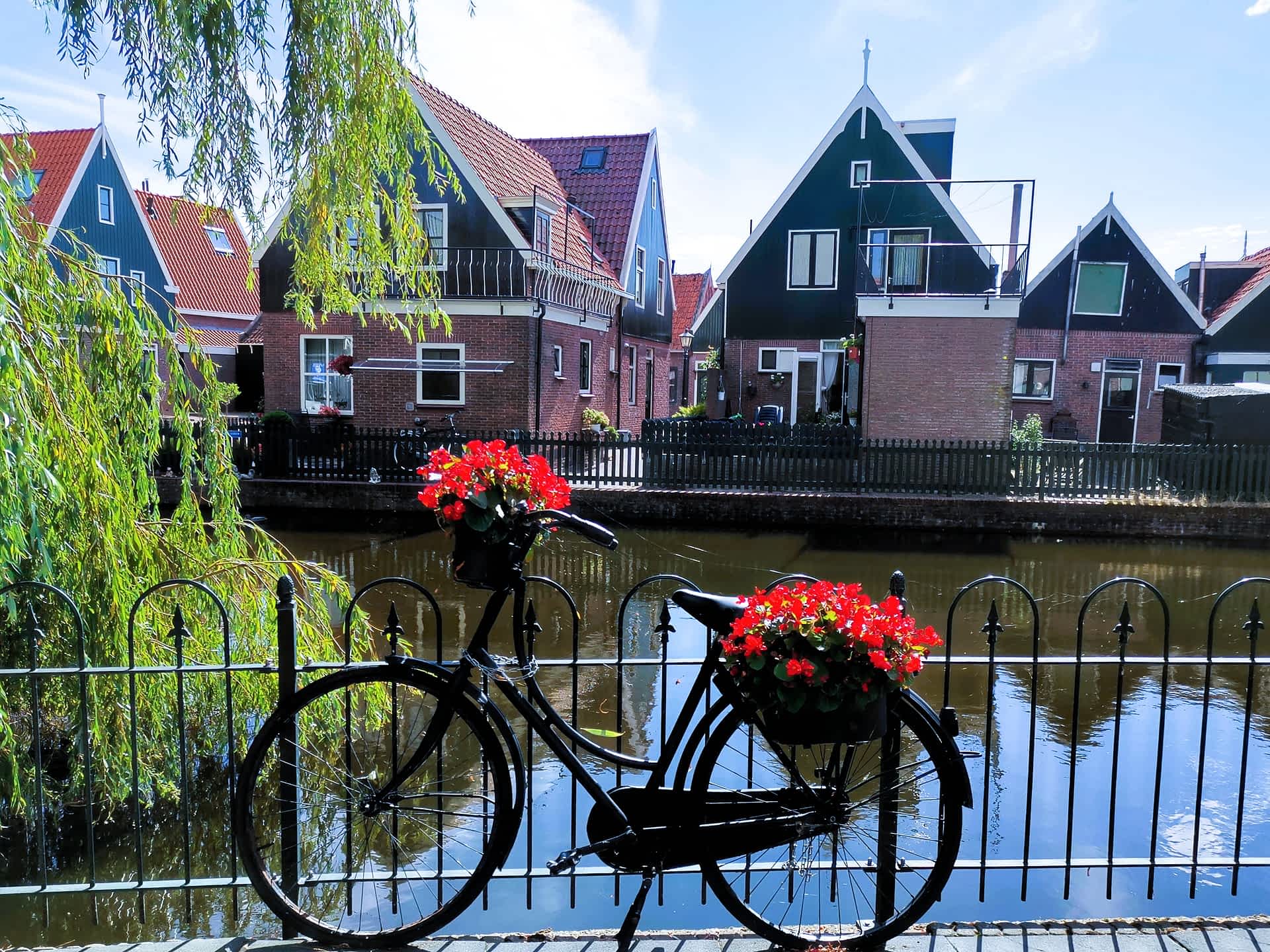 Ein klassisches schwarzes Fahrrad mit roten Blumenkästen am Kanal